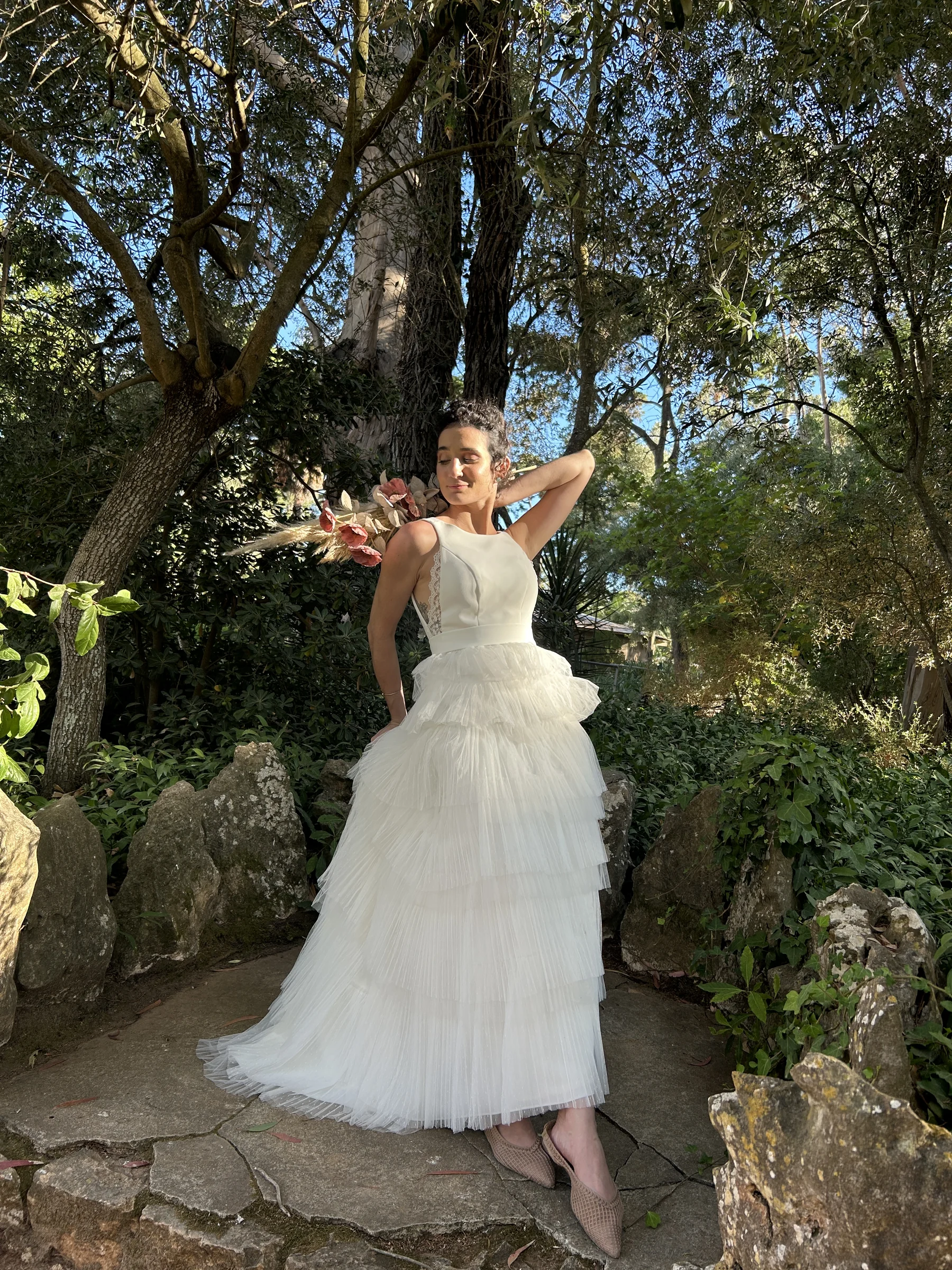 Noiva com vestido branco plissado em camadas no jardim