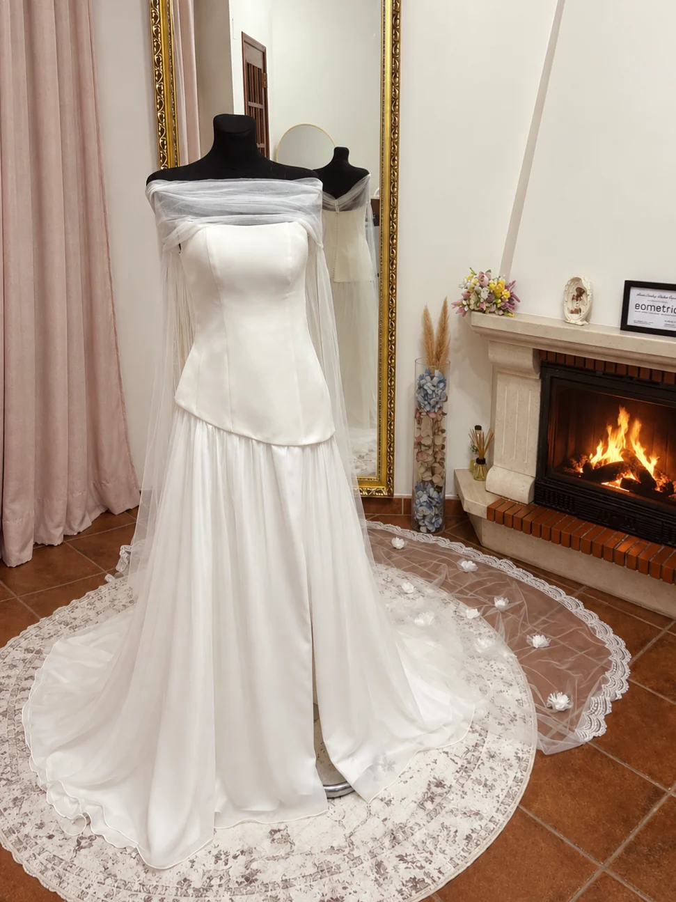 Vestido branco exposto no atelier diante de uma lareira